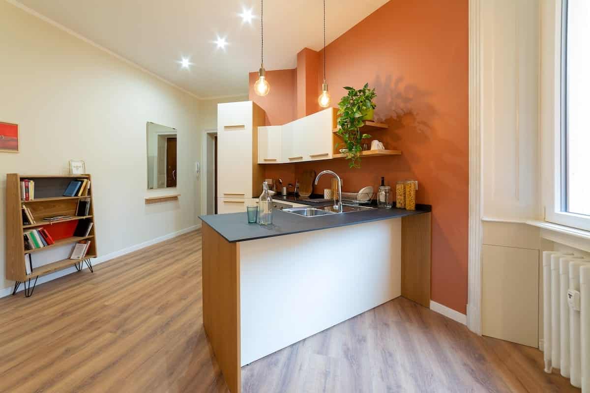 Cucina su misura con penisola ristrutturata da Creo Casa a Milano con legno e dettagli arancioni