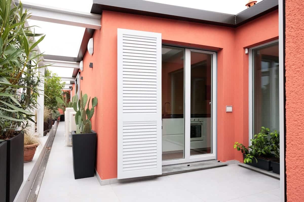 Terrazzo ristrutturato da Creo Casa Milano con pareti color corallo e piante