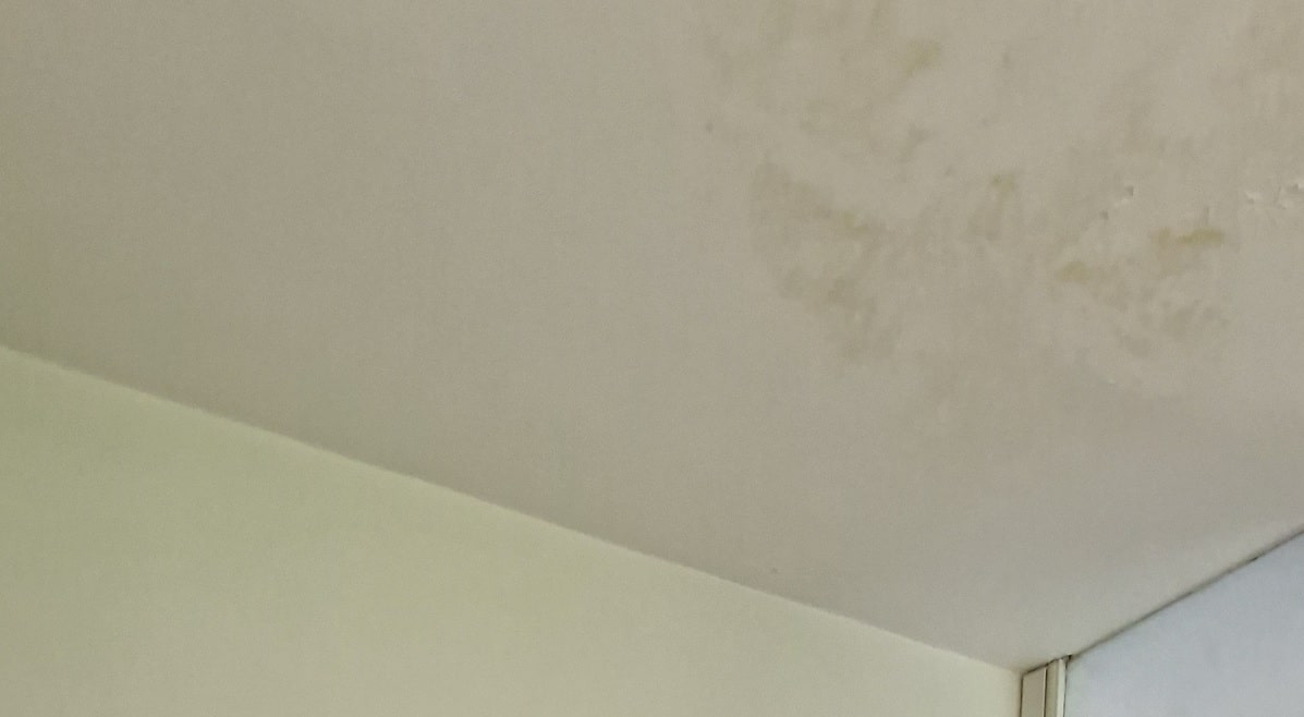 Immagine ravvicinata di un soffitto e muro scrostato, da trattare in fase di ristrutturazione della casa